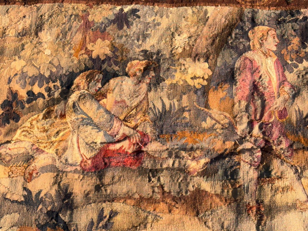 A 19th-century woven wall tapestry depicting a pastoral landscape scene with figures in romantic attire within a detailed floral border. View VII