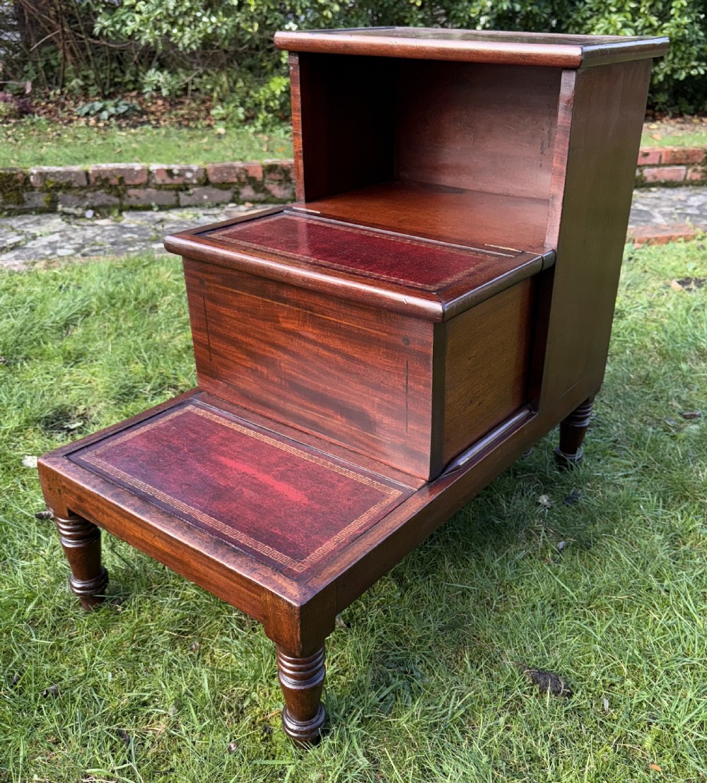 A set of three-tiered Victorian mahogany library steps featuring gold-tooled red leather inserts on the treads and turned wooden front legs.