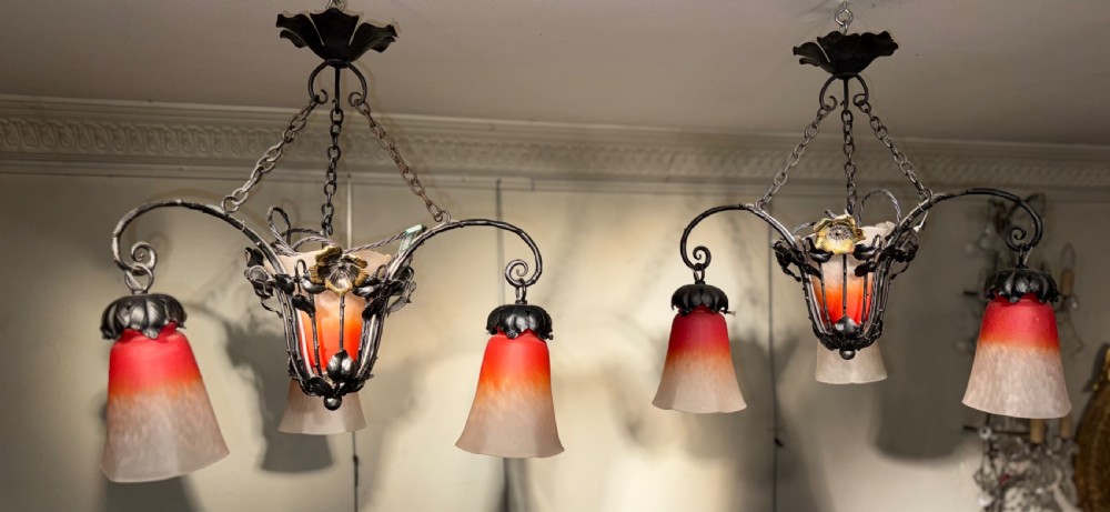 A pair of French Art Nouveau wrought iron chandeliers with floral frameworks supporting mottled orange and cream glass shades. View II