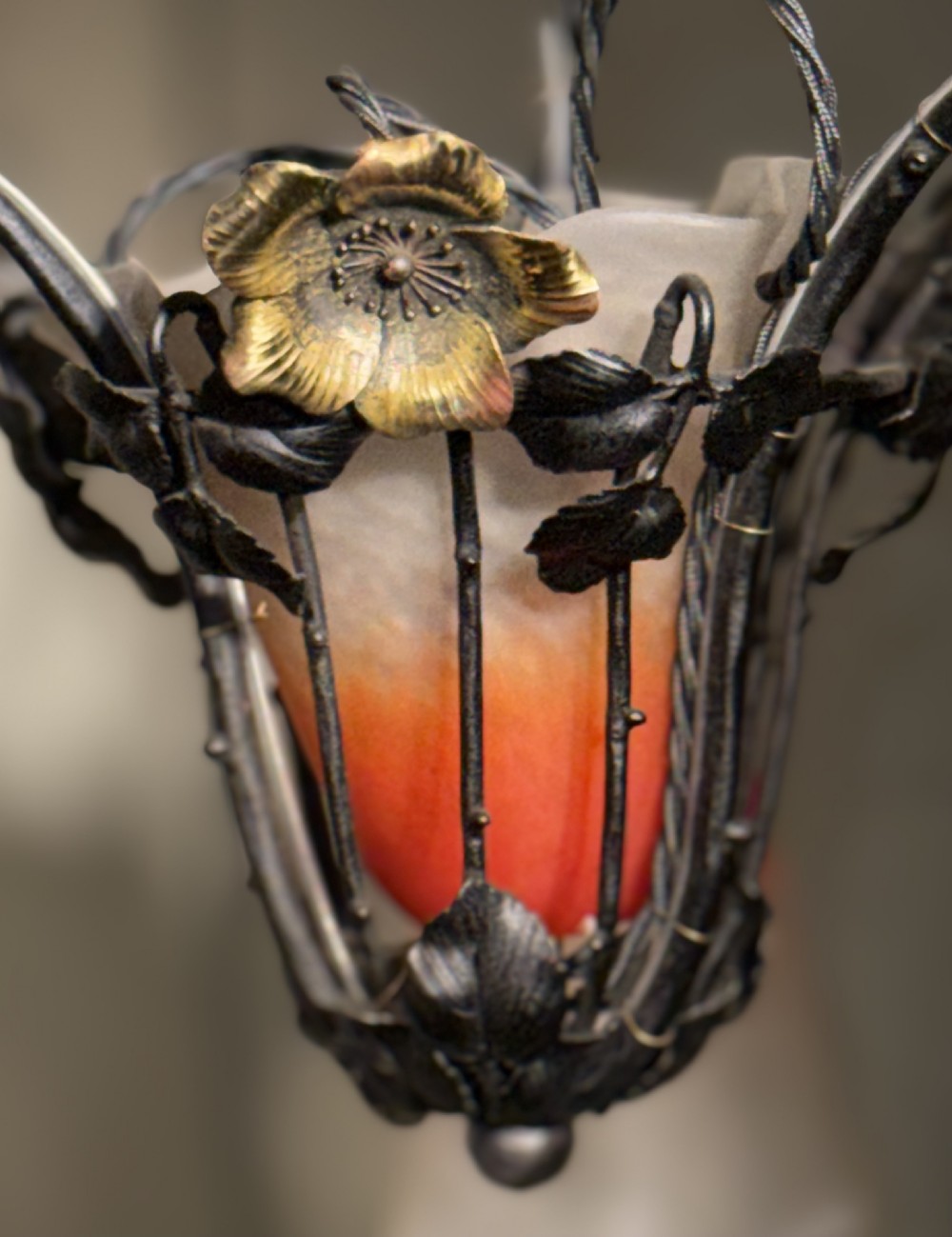 A pair of French Art Nouveau wrought iron chandeliers with floral frameworks supporting mottled orange and cream glass shades. View III