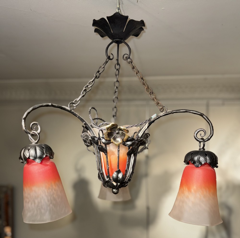 A pair of French Art Nouveau wrought iron chandeliers with floral frameworks supporting mottled orange and cream glass shades. View V