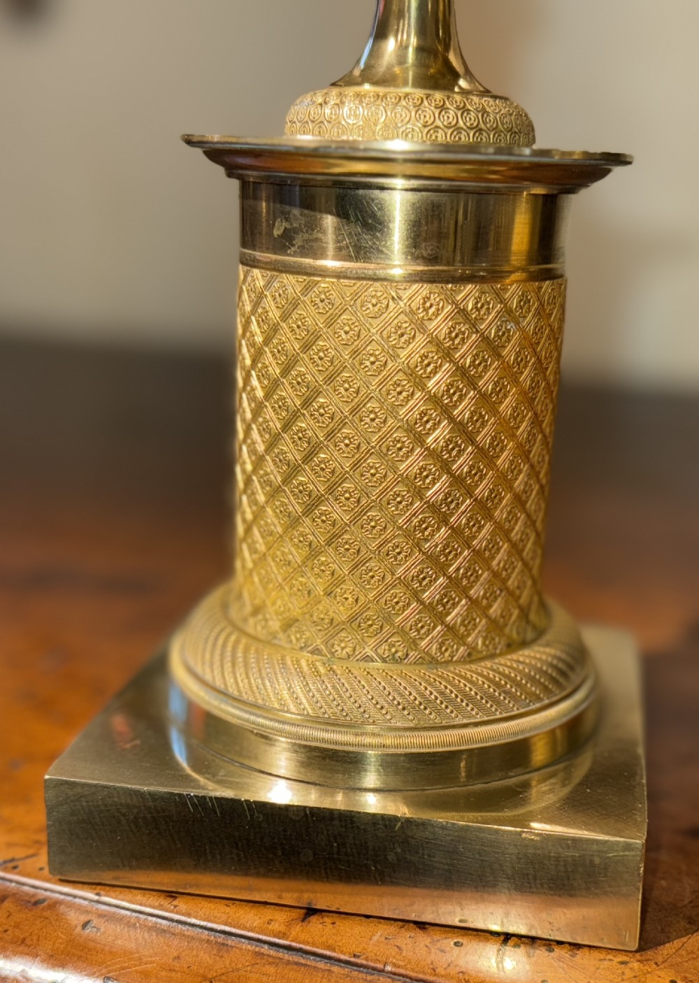 A pair of French Empire gilt bronze tazzas featuring pierced rims, engine-turned lattice patterns, pedestal stems, and square plinth bases. View II