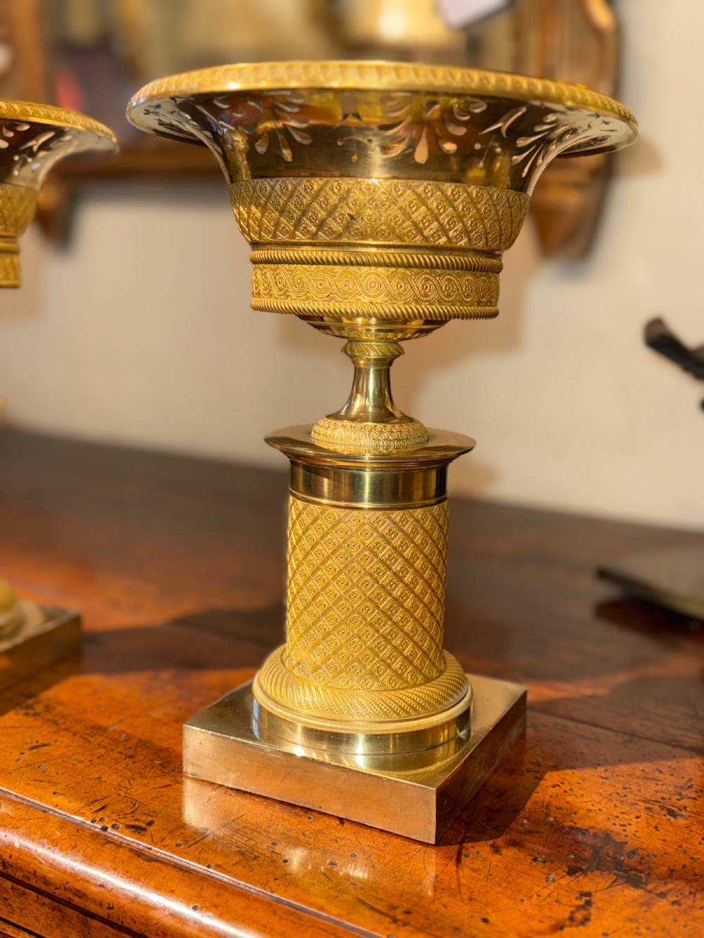 A pair of French Empire gilt bronze tazzas featuring pierced rims, engine-turned lattice patterns, pedestal stems, and square plinth bases. View IV