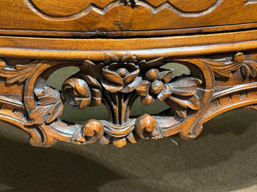 An 18th-century French Provincial walnut commode featuring two wide drawers with ornate brass handles, panelled carvings, and cabriole legs. View IX