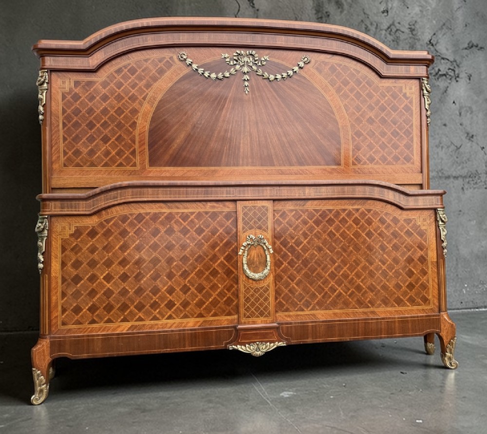 A French Louis XVI style kingsize bedstead with geometric diamond parquetry wood veneer and cast metal mounts on the headboard and footboard.