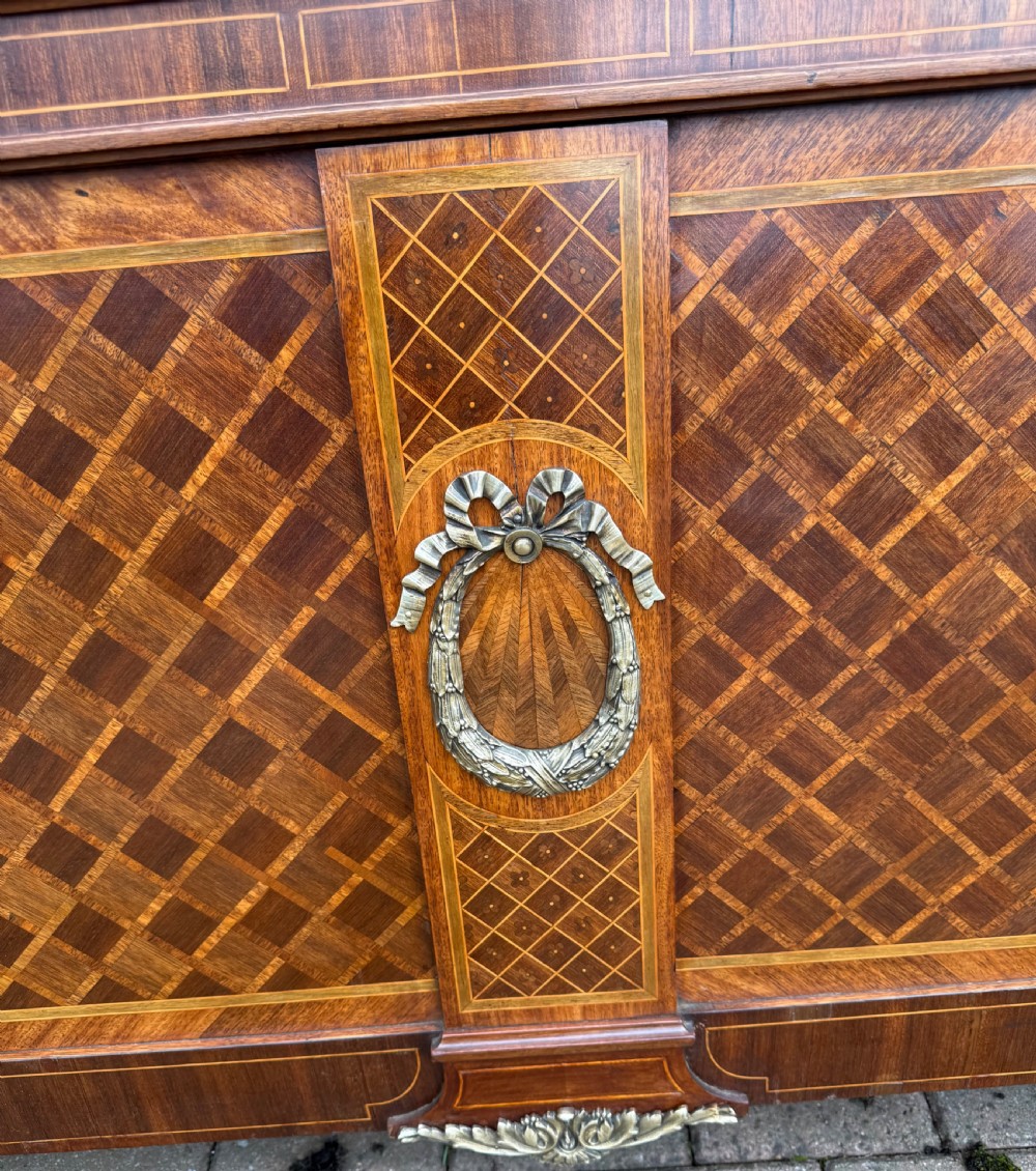 A French Louis XVI style kingsize bedstead with geometric diamond parquetry wood veneer and cast metal mounts on the headboard and footboard. View II