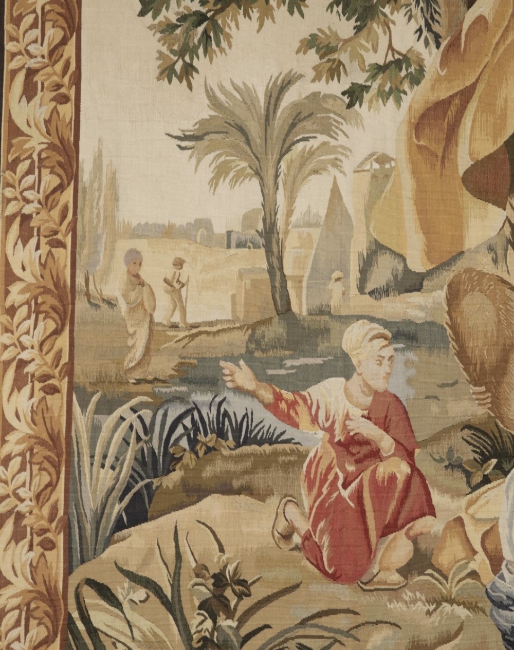 A large rectangular 19th-century French Aubusson style woven tapestry depicting figures under palm trees within a decorative foliage border. View VII