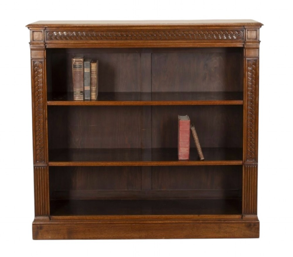 A late nineteenth-century Victorian walnut open bookcase featuring three horizontal shelves, carved frieze detail, and fluted side pilasters on a solid plinth base.