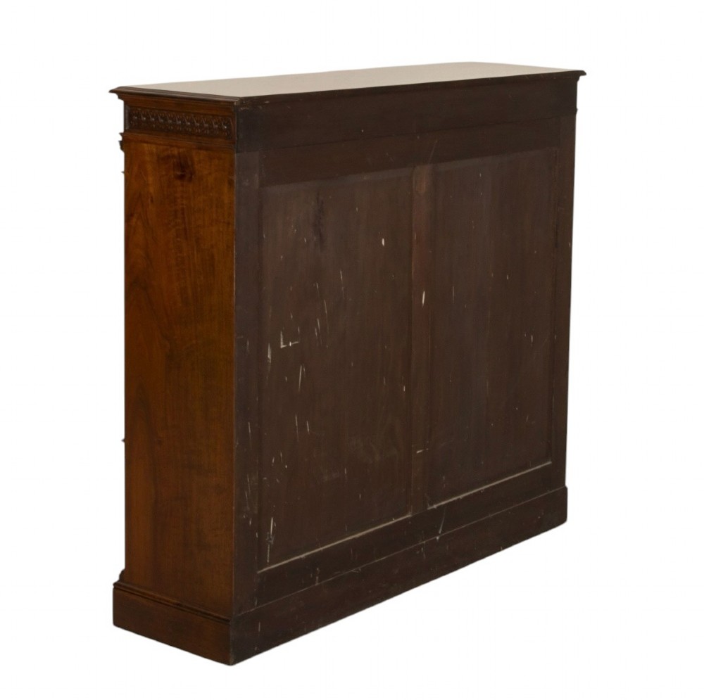 A late nineteenth-century Victorian walnut open bookcase featuring three horizontal shelves, carved frieze detail, and fluted side pilasters on a solid plinth base. View IV