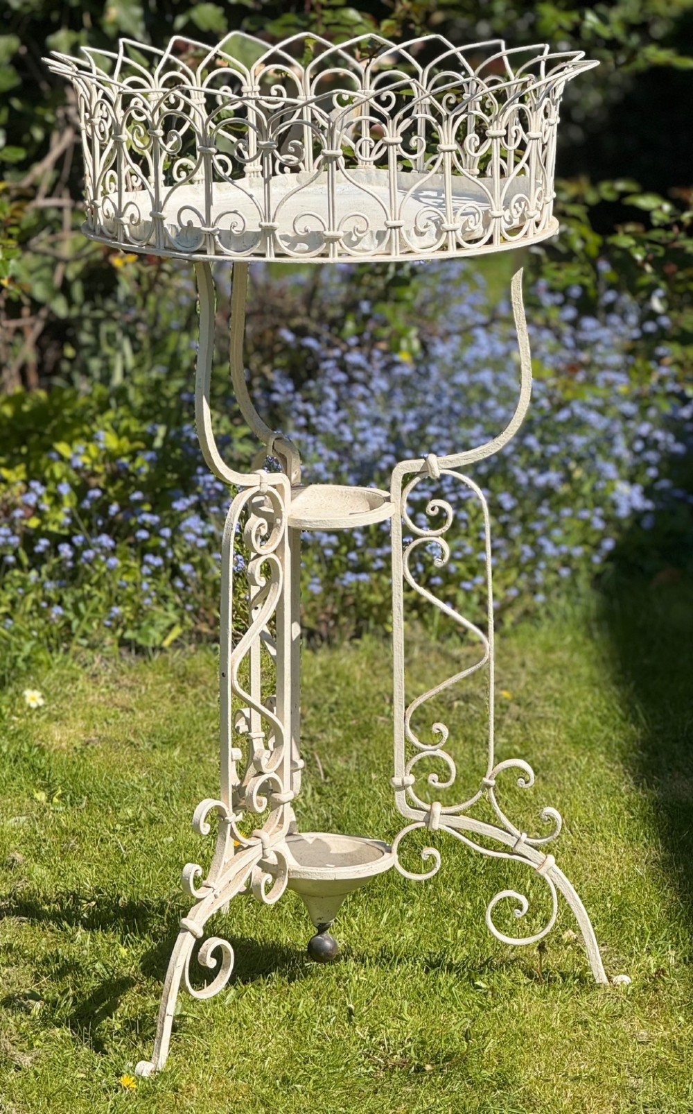 A nineteenth-century off-white painted wrought iron garden jardiniere featuring a tripod scrolled base and a lattice basket top.