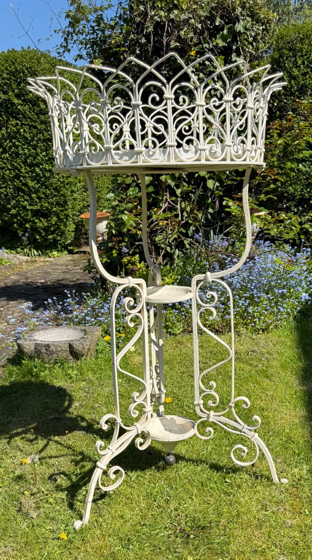 A nineteenth-century off-white painted wrought iron garden jardiniere featuring a tripod scrolled base and a lattice basket top. View II