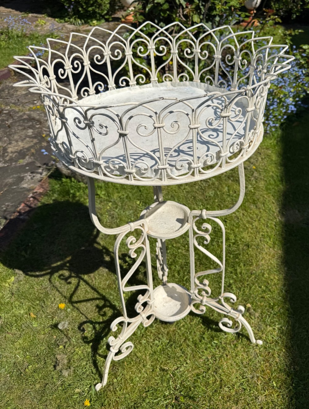 A nineteenth-century off-white painted wrought iron garden jardiniere featuring a tripod scrolled base and a lattice basket top. View III