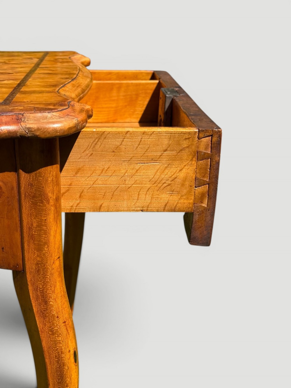A golden-brown burr wood side table featuring a serpentine-edged top with inlay, a single drawer with a keyhole, and four slender cabriole legs. View V