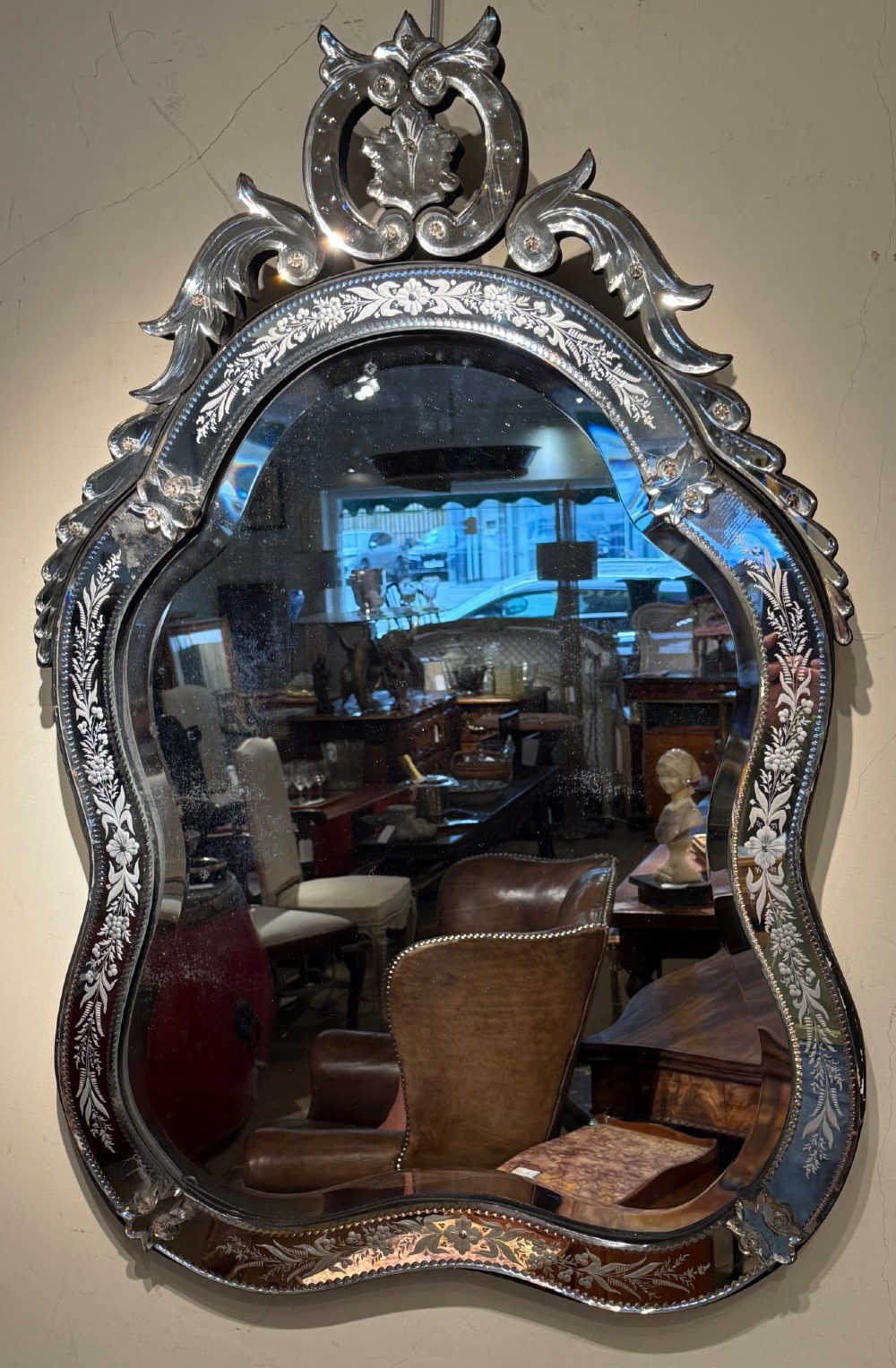 An ornate Venetian wall mirror featuring hand-etched floral glass borders, a decorative crest pediment, and a scalloped inner frame. View VI