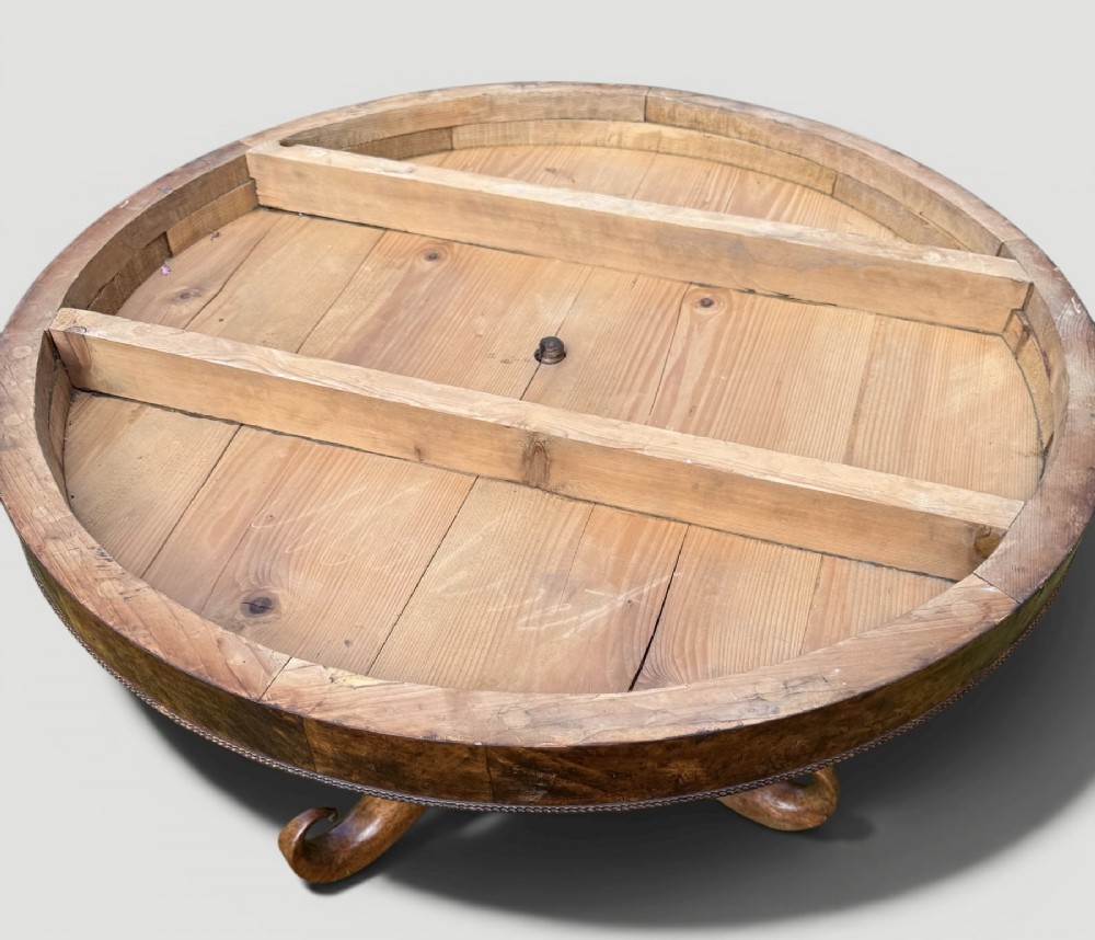 A circular antique gueridon table featuring a grey veined marble top, a figured walnut apron, a turned central pedestal, and scrolled tripod legs on castors. View III