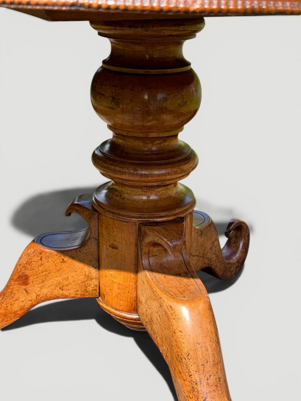 A circular antique gueridon table featuring a grey veined marble top, a figured walnut apron, a turned central pedestal, and scrolled tripod legs on castors. View IV