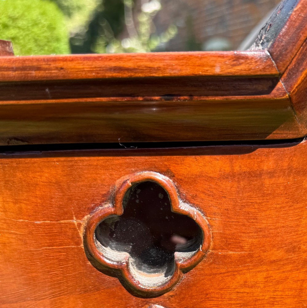 An antique mahogany Gothic Revival display cabinet on stand with pointed arch glass doors, side panels, and a lower drawer. View IV