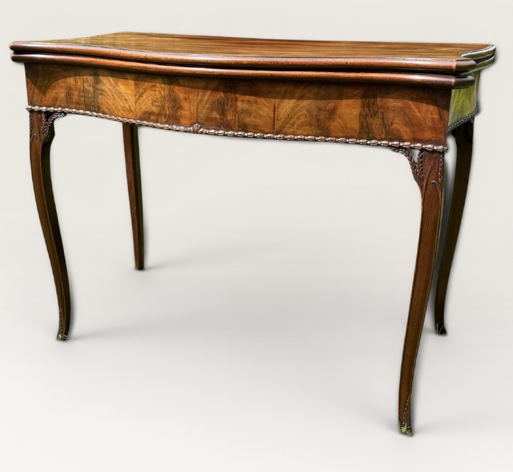 An antique warm brown mahogany card table with a serpentine front, carved cabriole legs, and a hinged fold-over top. View III