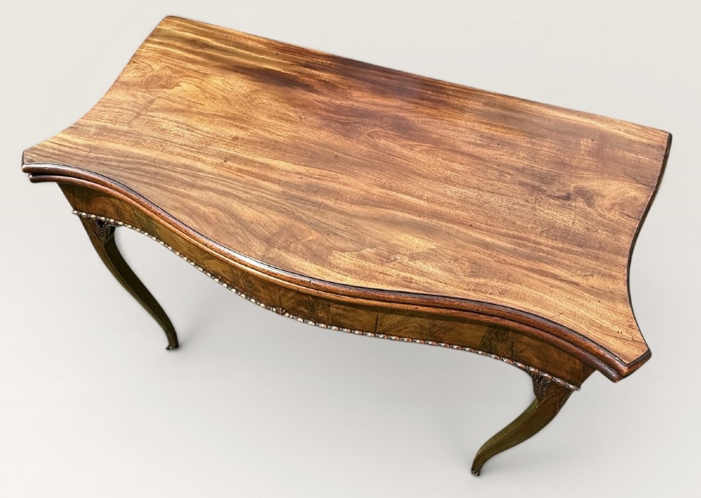 An antique warm brown mahogany card table with a serpentine front, carved cabriole legs, and a hinged fold-over top. View IV