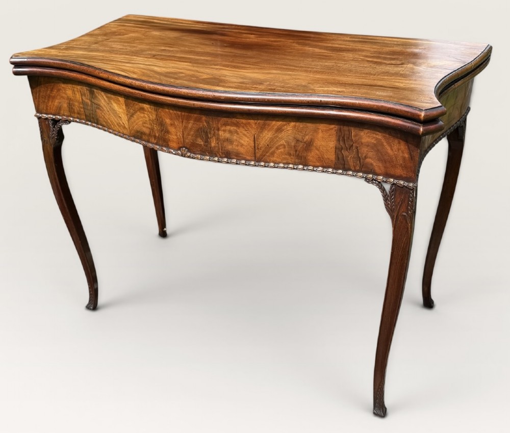 An antique warm brown mahogany card table with a serpentine front, carved cabriole legs, and a hinged fold-over top. View VII