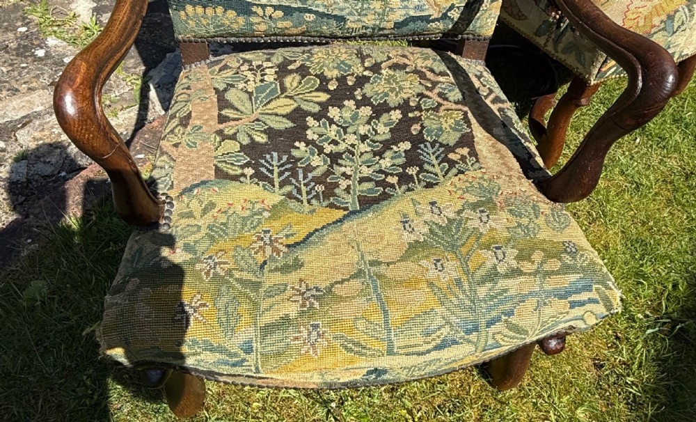 A pair of 18th-century carved wood armchairs featuring detailed botanical and pictorial needlepoint tapestry upholstery with brass studding. View VI