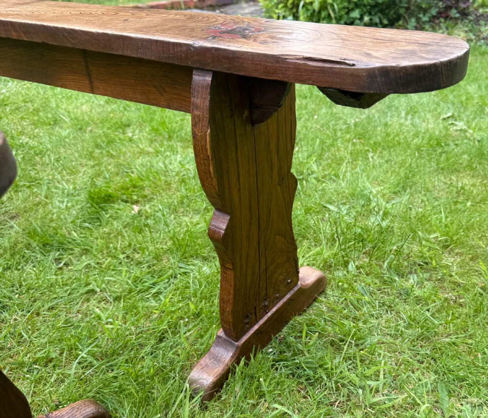 A pair of long French rustic oak benches with shaped trestle legs and smooth rounded seats showing distinct timber grain. View III