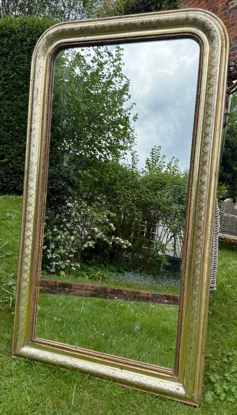 A large rectangular Louis Philippe mirror featuring rounded upper corners, a silver gilt frame with etched cross-hatch patterning, and a beaded inner border.