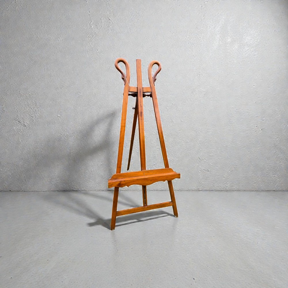 A tall warm brown wooden floor-standing tripod easel featuring carved swan head finials at the top arch and a wide horizontal support shelf. View III