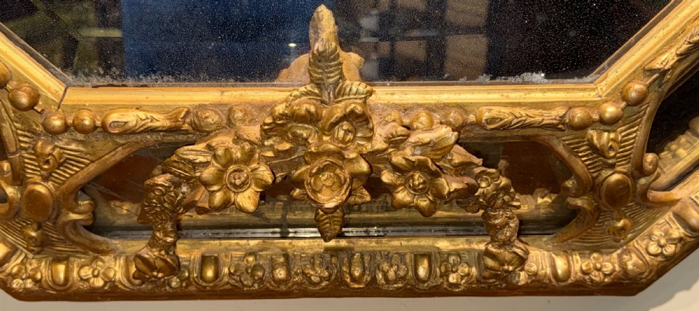 A 19th-century octagonal giltwood cushion wall mirror featuring ornate cresting, egg-and-dart moulding, and angled perimeter mirror plates. View IV