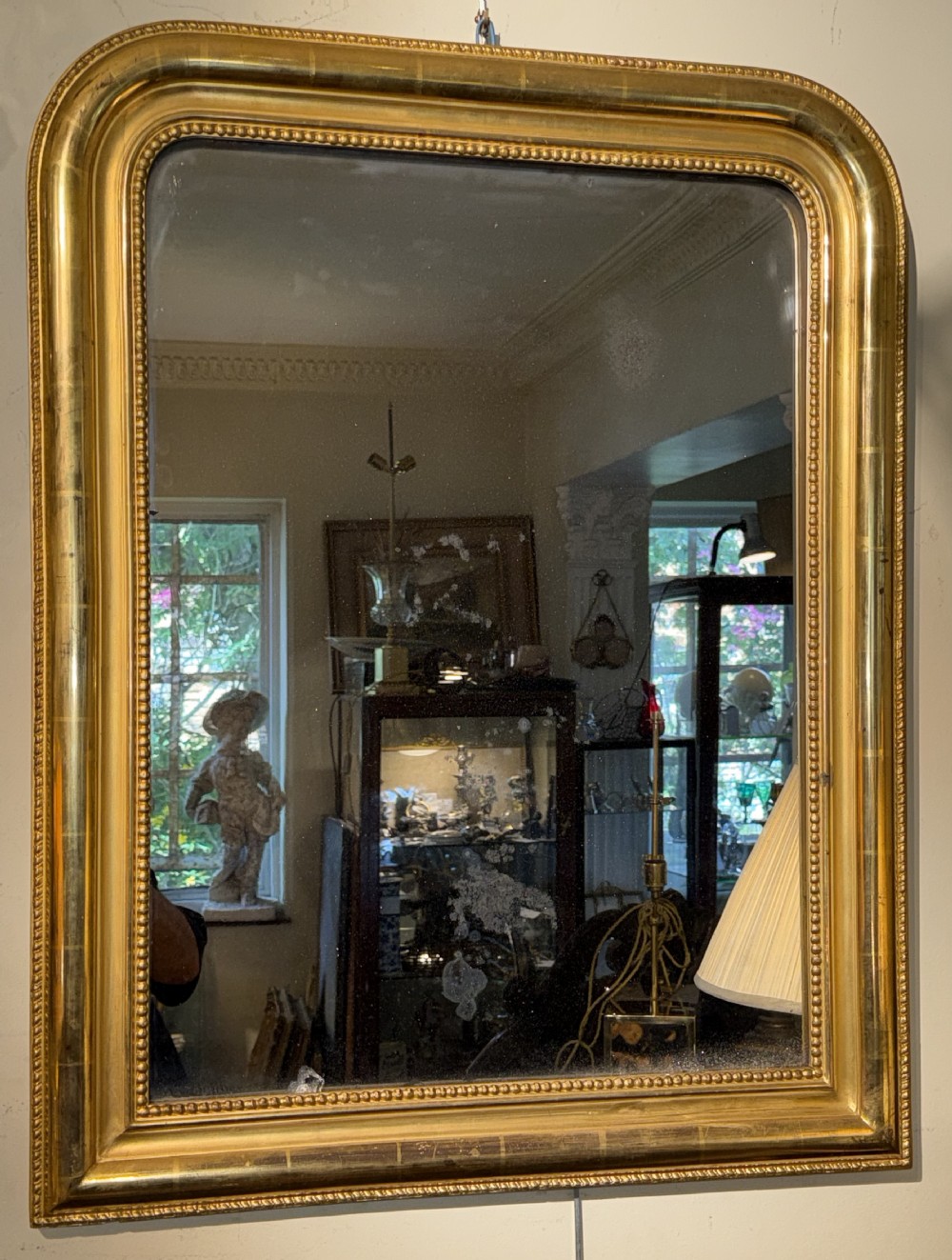 A rectangular French Louis Philippe giltwood wall mirror featuring rounded upper corners and a beaded inner moulding.
