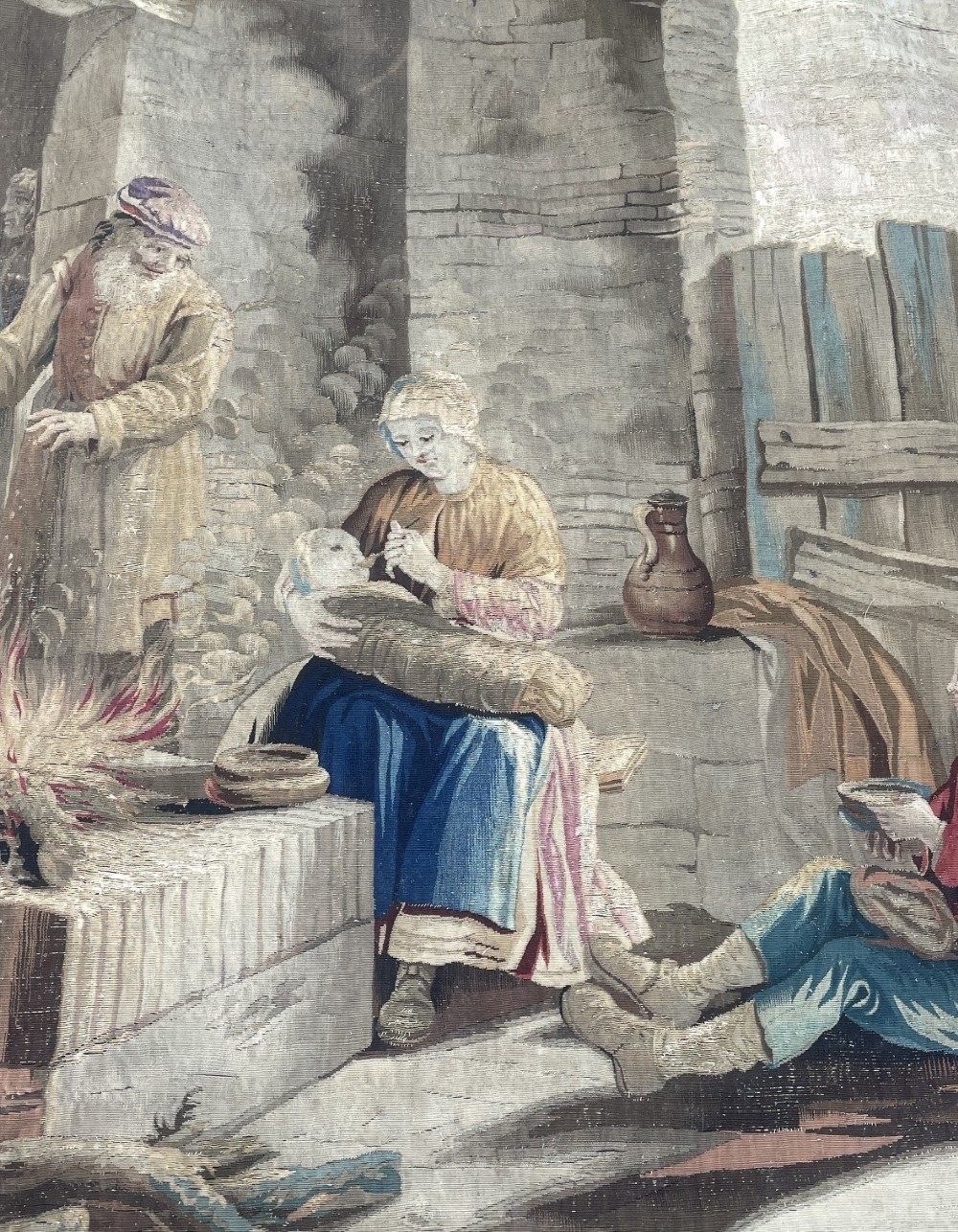 A late seventeenth-century Brussels woven wool and silk tapestry depicting a rustic genre scene with figures near a stone hearth in neutral brown and beige tones. View V