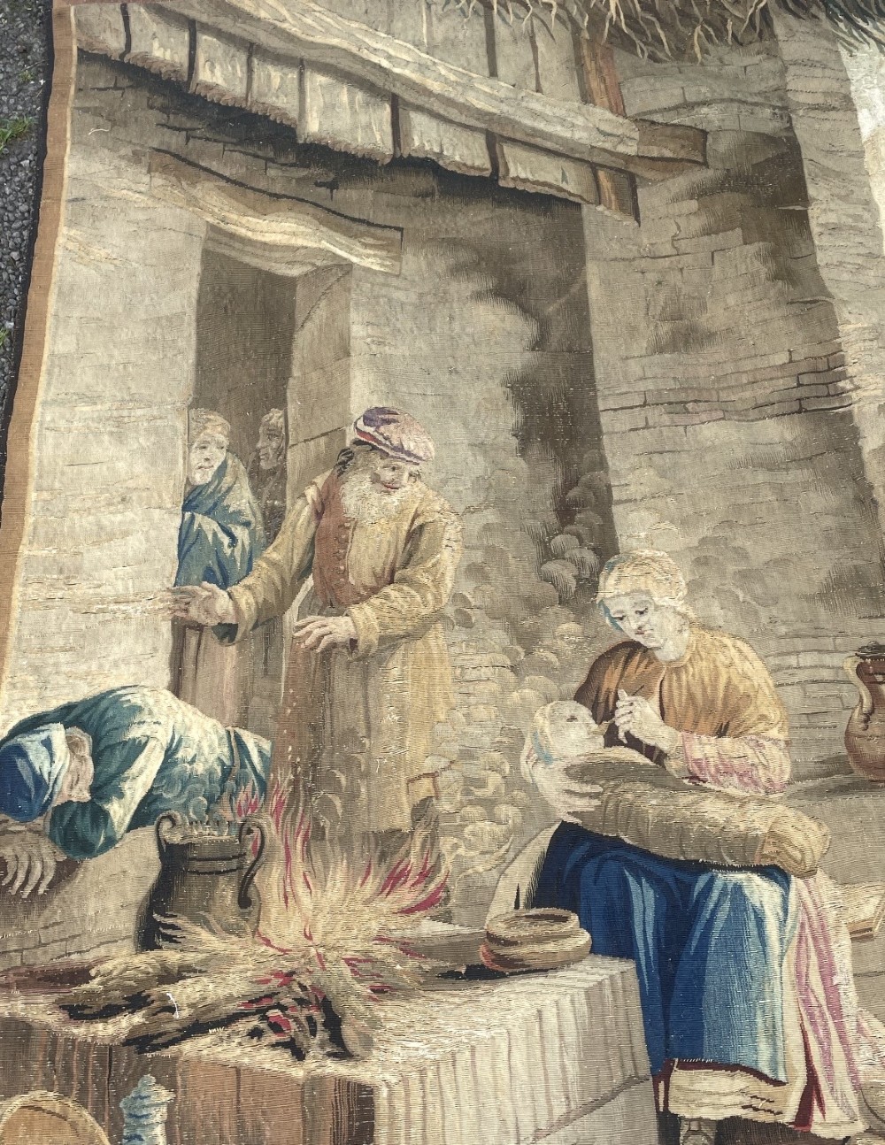 A late seventeenth-century Brussels woven wool and silk tapestry depicting a rustic genre scene with figures near a stone hearth in neutral brown and beige tones. View VI