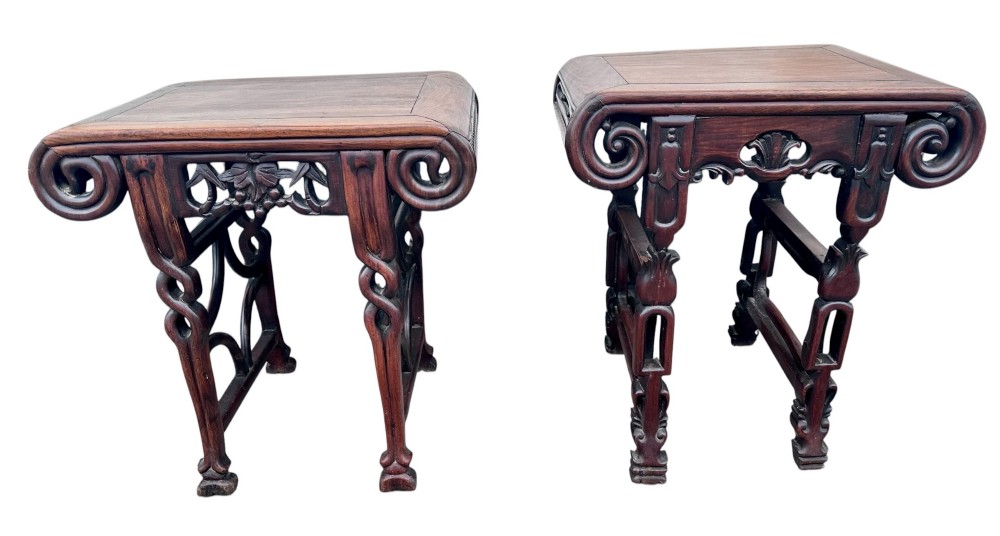 A pair of 19th-century carved dark hardwood side tables with scrolled tops and pierced floral aprons.