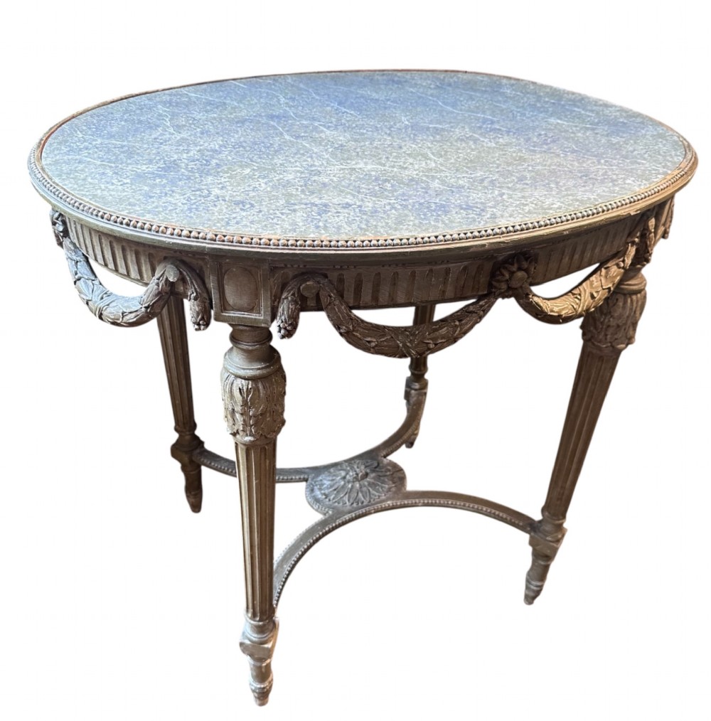 A 19th-century French Louis XVI style oval occasional table featuring a blue-green marble top, carved draped swags, fluted legs, and a central rosette stretcher.