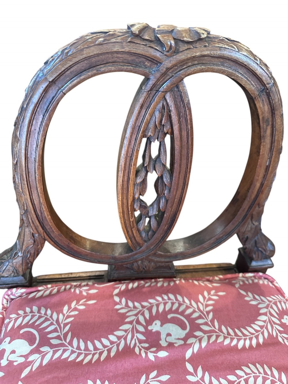 A late 19th-century French carved walnut window seat featuring raised oval ends, fluted tapered legs, and a pink patterned upholstered seat cushion. View II