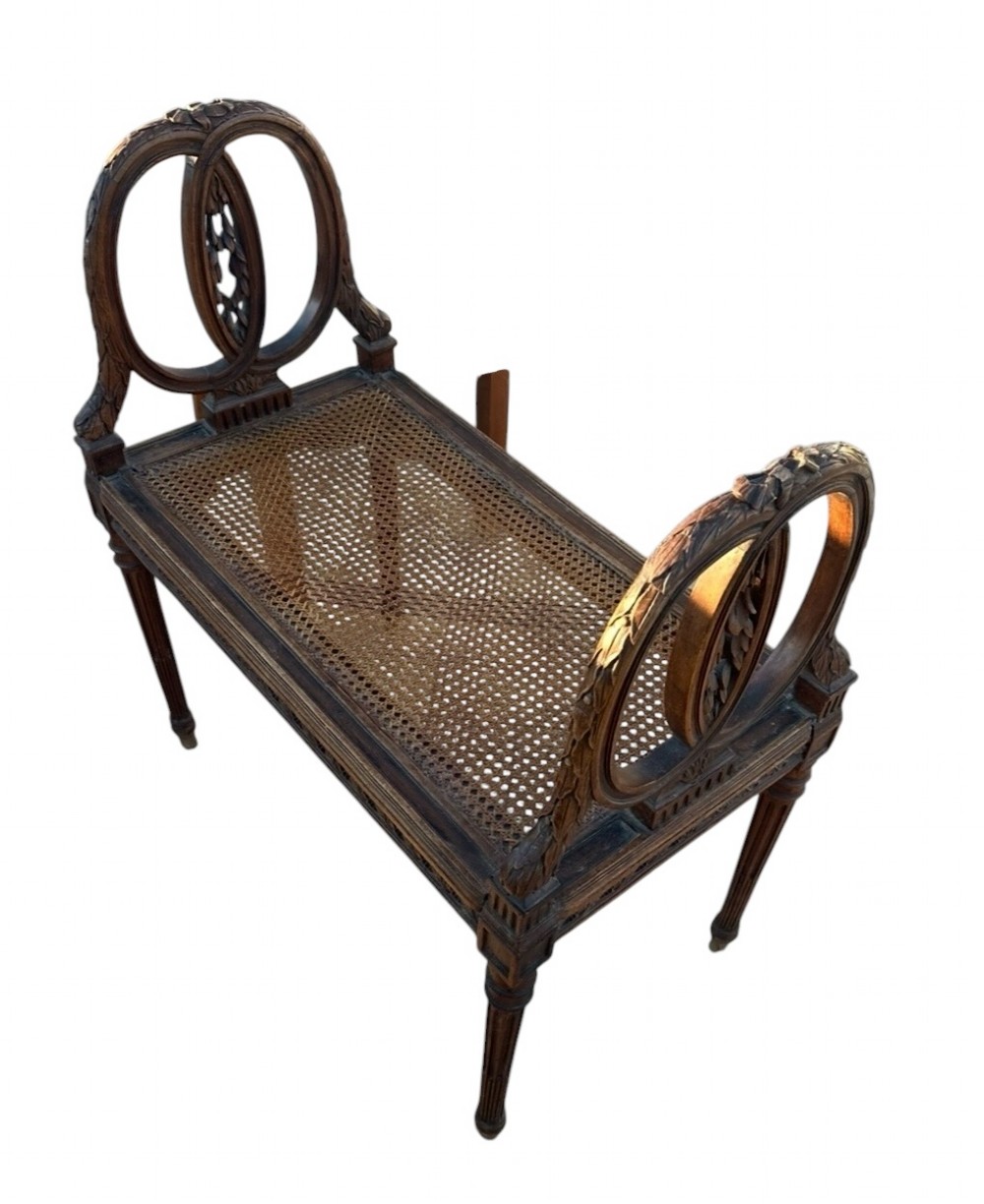 A late 19th-century French carved walnut window seat featuring raised oval ends, fluted tapered legs, and a pink patterned upholstered seat cushion. View III