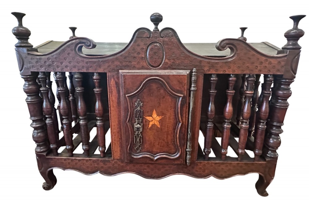 An 18th-century French fruitwood panetiere bread cage featuring turned wood balusters, carved pediment finials, and a central cupboard door with an inlaid star and iron hardware.