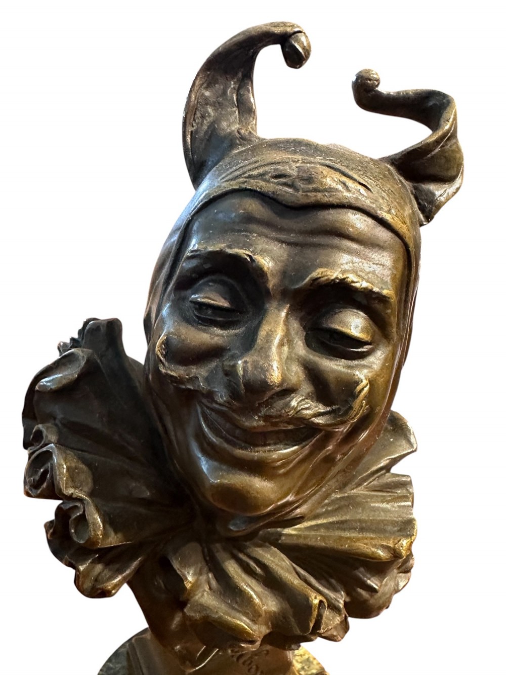 A 19th-century patinated bronze bust depicting the court jester Triboulet wearing a horned cap and ruff collar, mounted on a green marble cylindrical base with a brass title plaque. View II