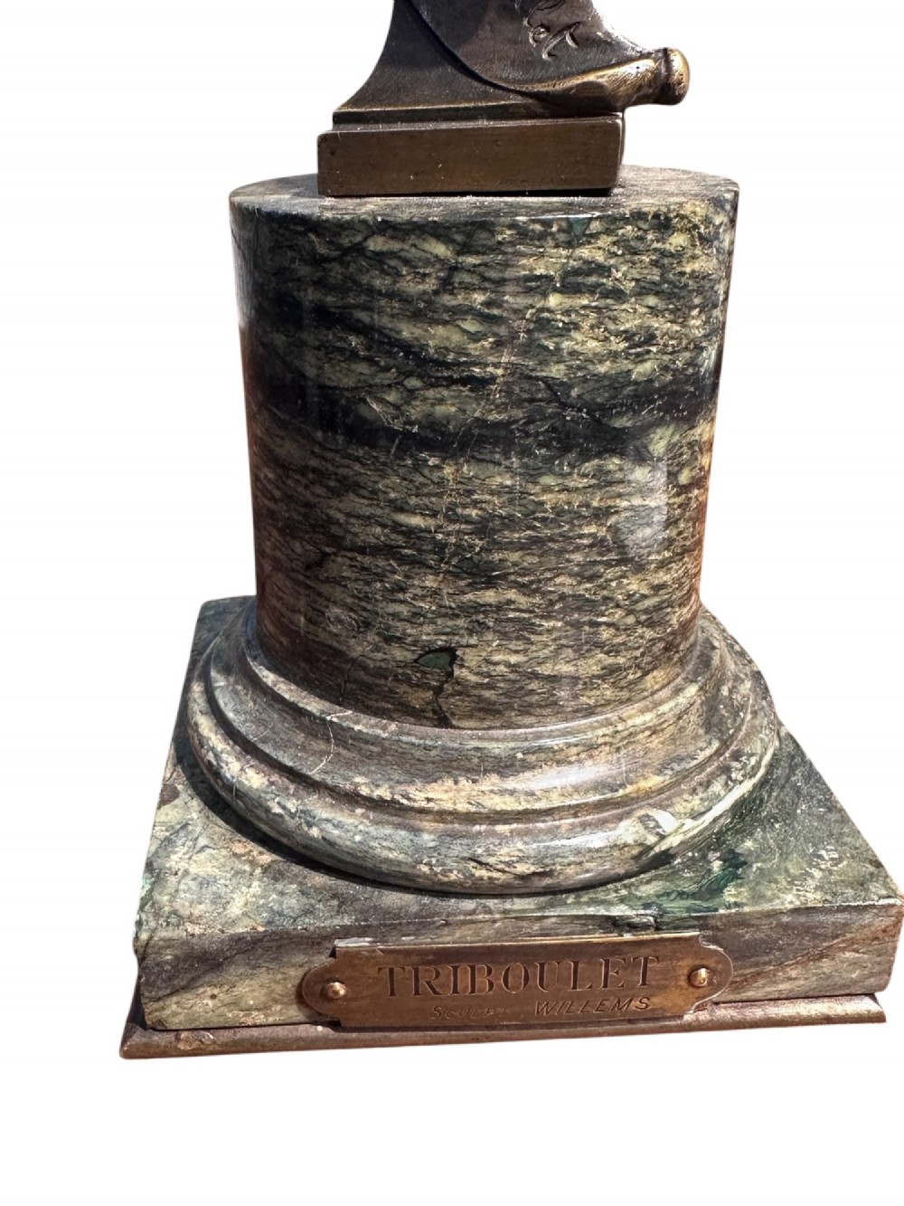 A 19th-century patinated bronze bust depicting the court jester Triboulet wearing a horned cap and ruff collar, mounted on a green marble cylindrical base with a brass title plaque. View III