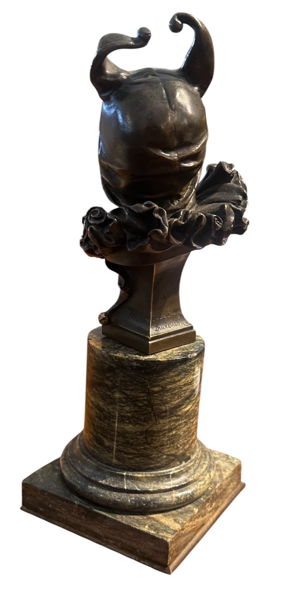 A 19th-century patinated bronze bust depicting the court jester Triboulet wearing a horned cap and ruff collar, mounted on a green marble cylindrical base with a brass title plaque. View IV