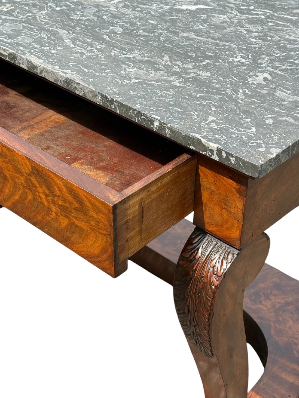 A 19th-century French Louis Philippe mahogany console table featuring a grey marble top, single frieze drawer, curved scroll front legs with acanthus carvings, and an incurved plinth base. View IV