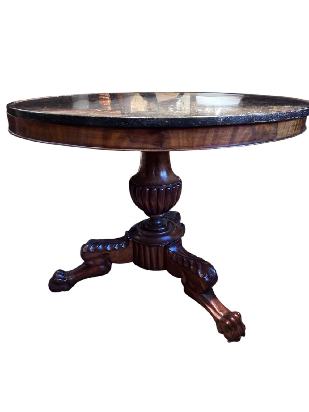 A 19th-century French Louis Philippe gueridon table featuring a dark polished marble top resting on a mahogany apron, turned pedestal column, and carved tripod feet.