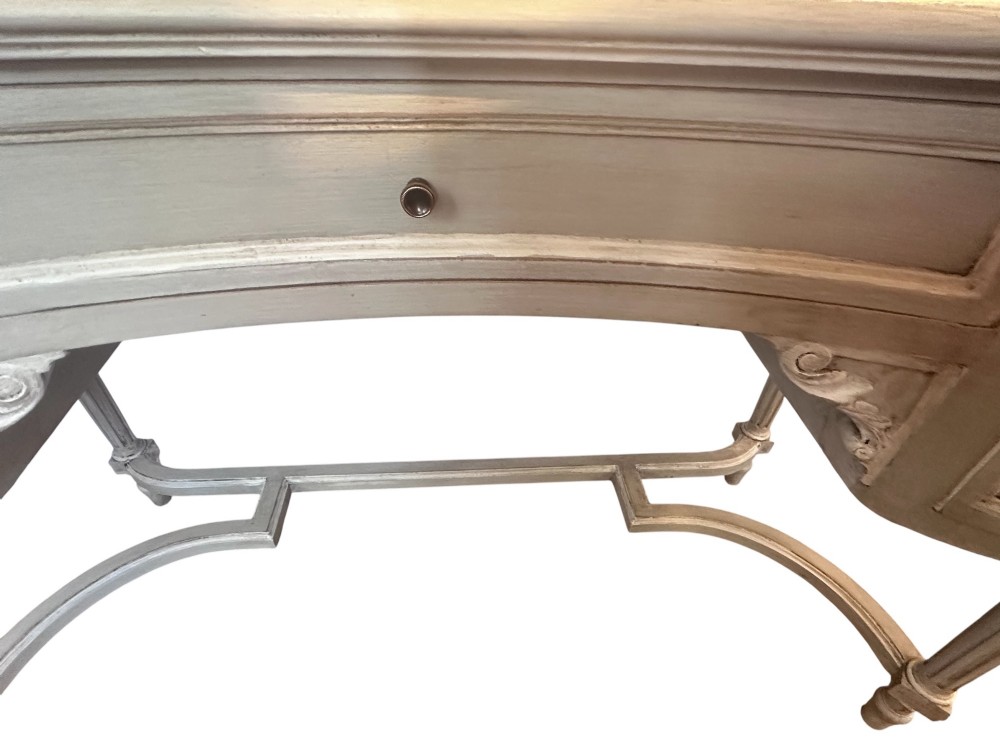 An off-white painted Edwardian kidney-shaped dressing table featuring five drawers, fluted legs, a glass inset top, and an attached triple oval mirror decorated with carved ribbon cresting. View III