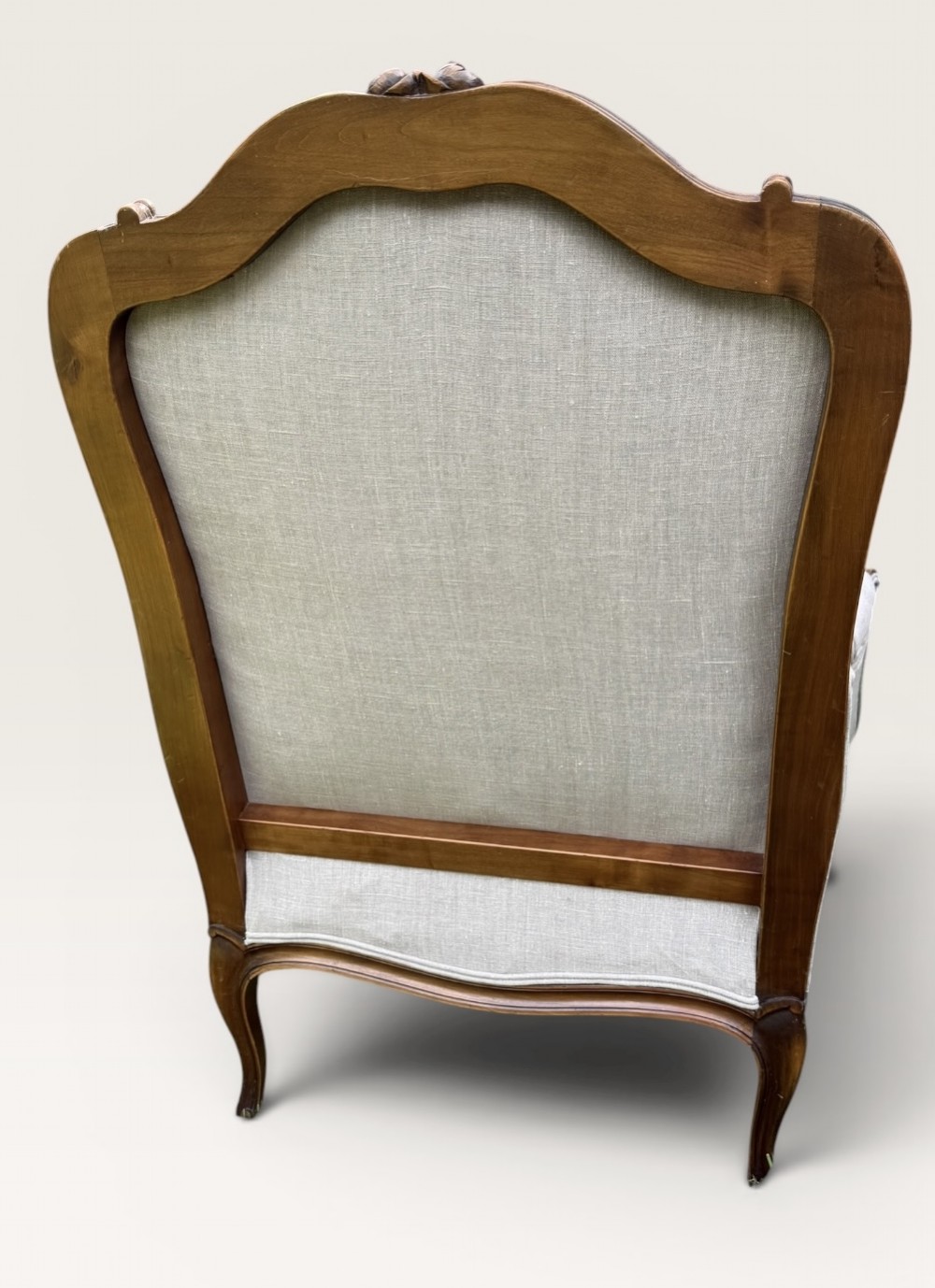 A pair of French Louis XV style Bergere armchairs featuring carved walnut wood frames and neutral light cream linen upholstery. View IV