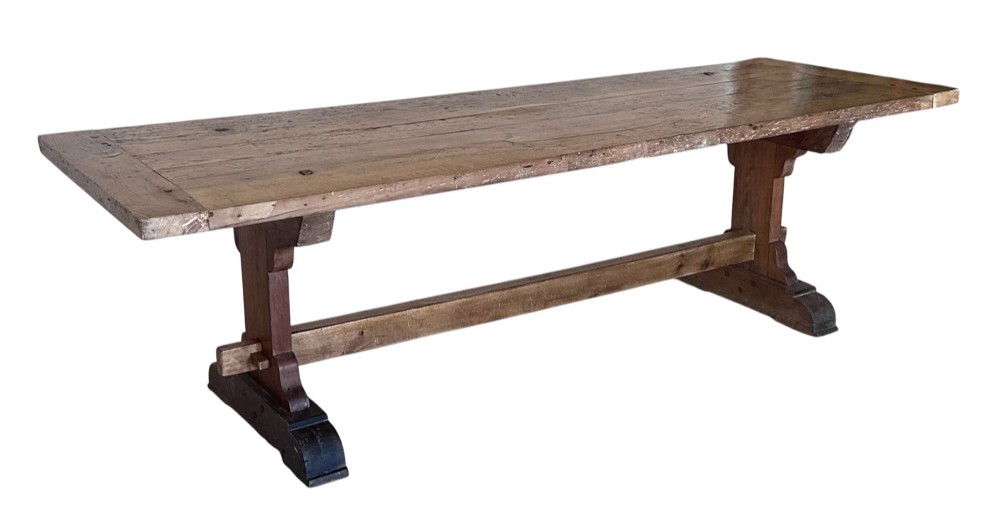 An 18th-century French refectory dining table constructed from beech timber with a solid plank top and a trestle base connected by a low stretcher.