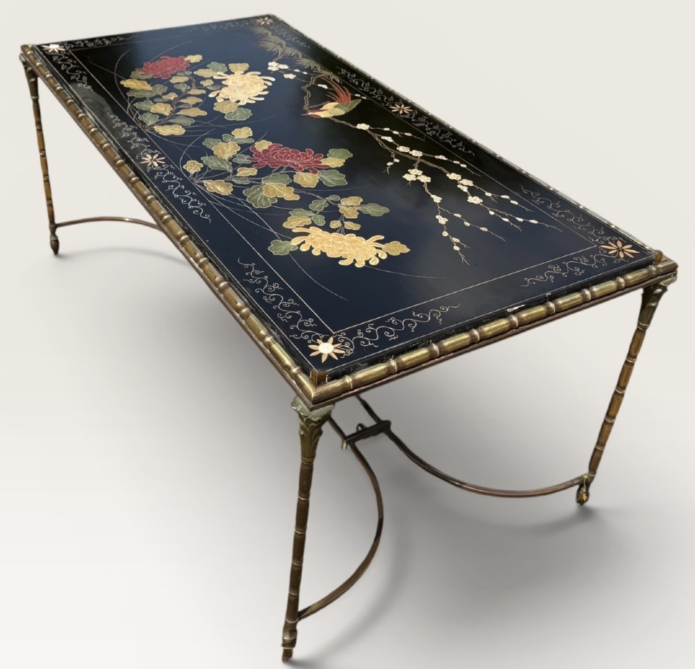 A rectangular mid-century low table featuring a faux-bamboo brass frame, X-form stretchers, and a black lacquered top decorated with colourful Chinoiserie floral patterns. View V