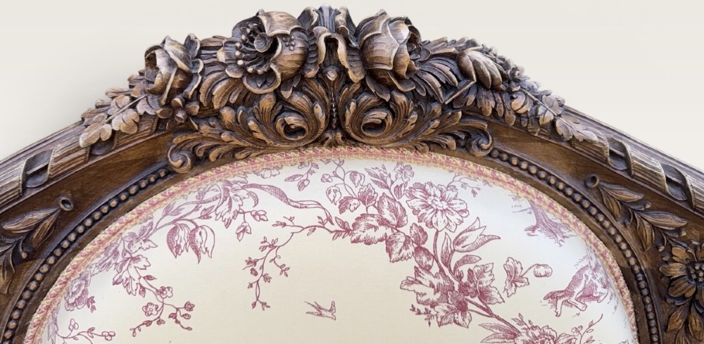 A pair of carved wooden French bergere armchairs upholstered in cream and burgundy toile de Jouy patterned fabric. View V