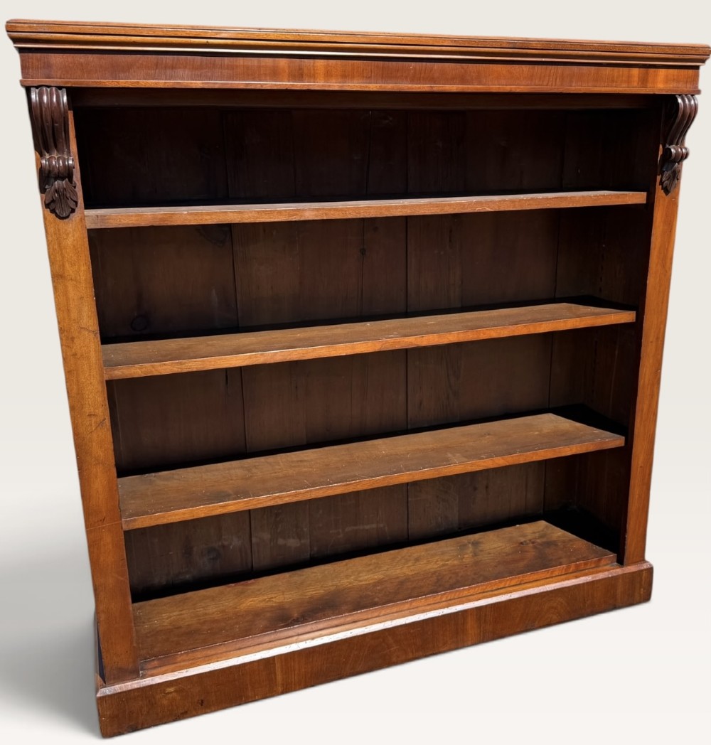A 19th-century Victorian open walnut bookcase featuring four tiers, decorative carved corbels beneath a moulded top cornice, and a solid plinth base. View II
