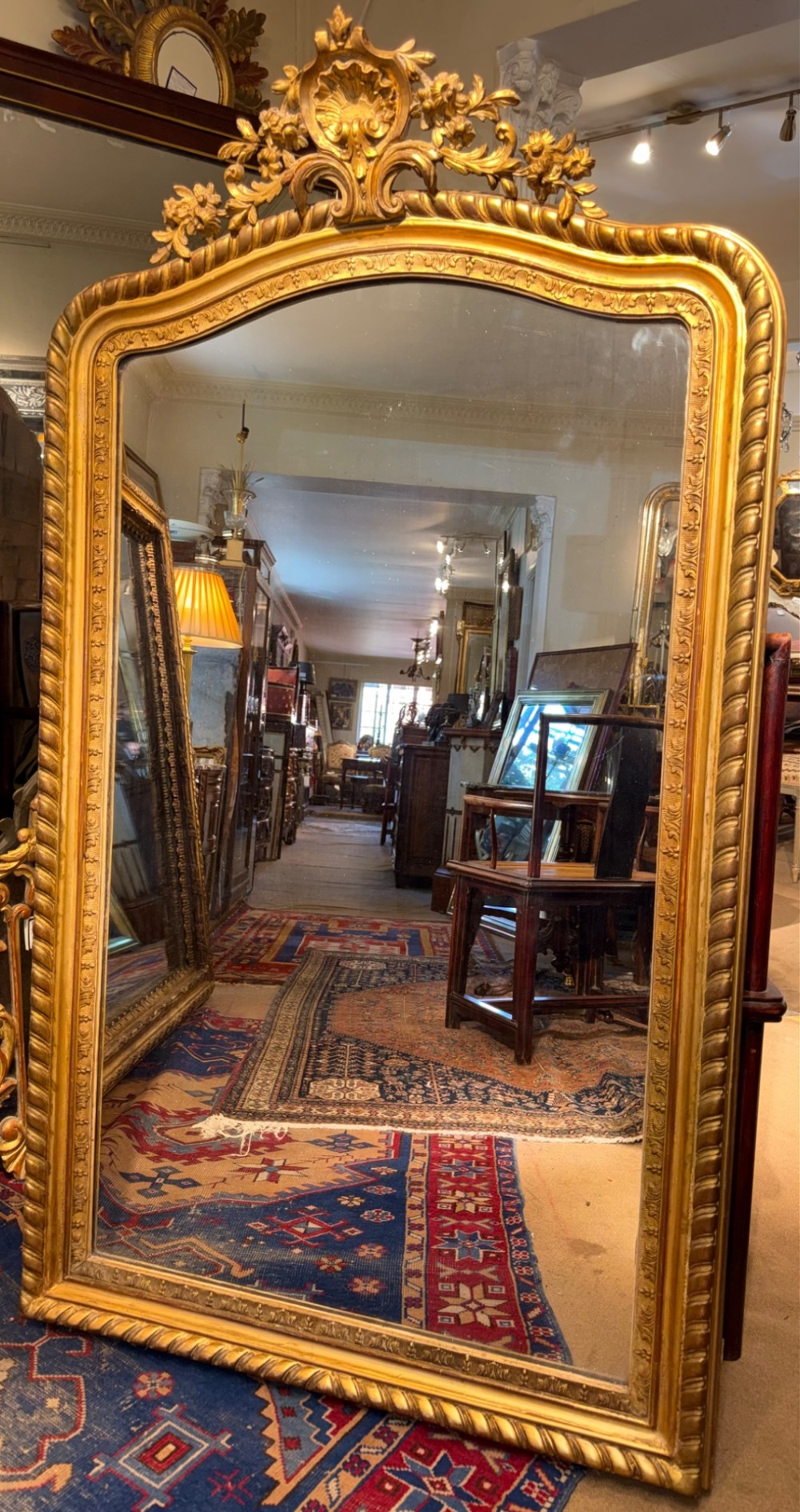 A 19th-century French giltwood overmantel mirror with an arched frame, rope twist moulding, and a central floral crest. View IV