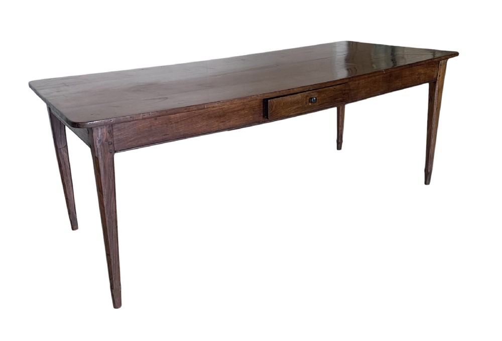 A large nineteenth-century French oak farmhouse table featuring a rectangular plank top, a frieze drawer with a wooden knob, and four tapered square legs.